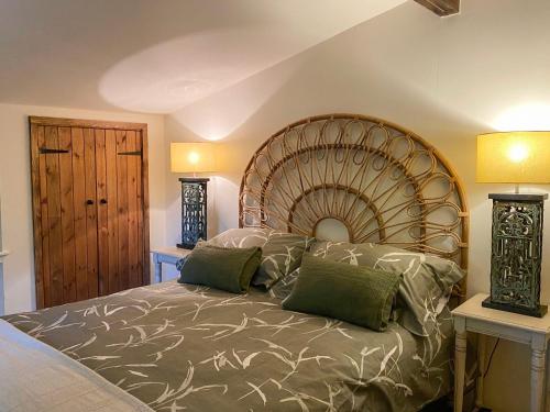 a bedroom with a large bed with green pillows at Chestnut Cottage - 27636 in Darenth