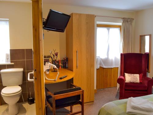 a room with a bathroom with a toilet and a tv at The Stable in Burscough
