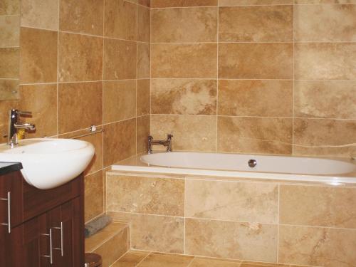a bathroom with a bath tub and a sink at Werescote View in Burlescombe