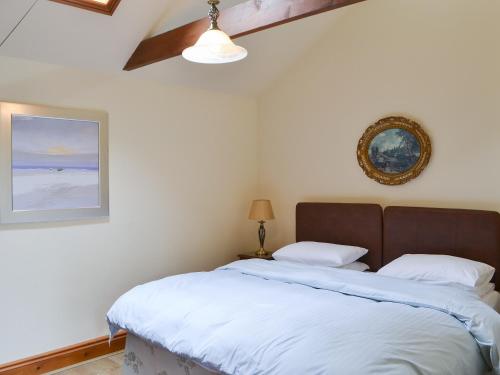 um quarto com uma cama e uma fotografia na parede em Cobweb Cottage em Elsdon