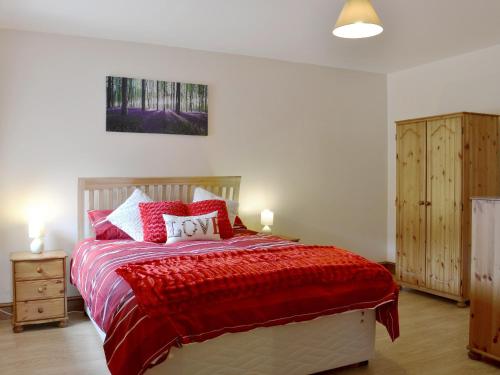 a bedroom with a bed with a red comforter at The Parlour - Op4 in Carmarthen