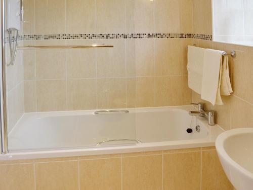 a bathroom with a bath tub and a sink at Isfryn in Llanystumdwy