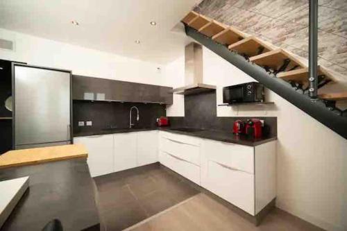 une cuisine avec des placards blancs et un escalier en colimaçon dans l'établissement LE MARQUIS - T3 Standing 100m2 250 mètres du Port, à Marseille