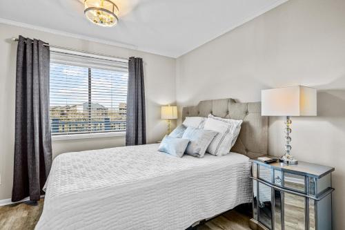 ein weißes Schlafzimmer mit einem Bett und einem Fenster in der Unterkunft Dunescape Villas 255 in Atlantic Beach