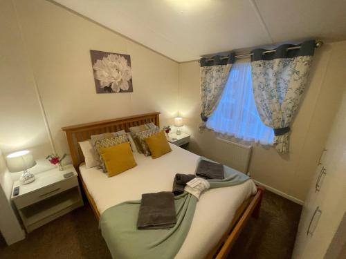a small bedroom with a bed and a window at Indulgence Lakeside Lodge i2 with hot tub, private fishing peg situated at Tattershall Lakes Country Park in Tattershall