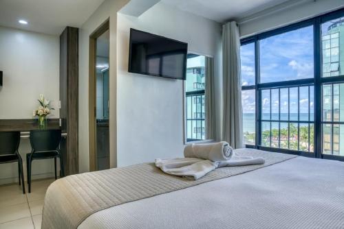 a bedroom with a bed with a television and a desk at Vistamar Hotel in Maceió