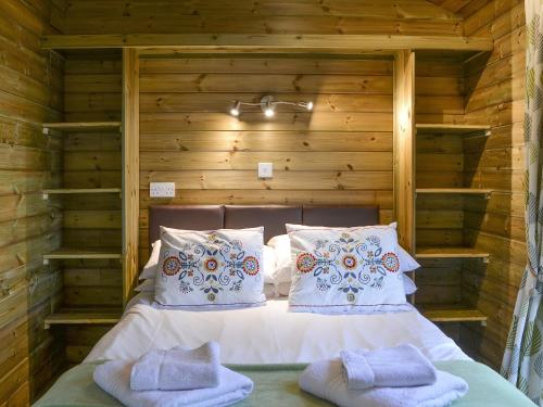 a bed in a wooden room with two pillows at Treehouse Cabin in Westward