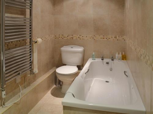 a bathroom with a toilet and a bath tub at Jumbos Stable in Alderminster