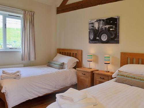 a bedroom with two beds and a tractor picture on the wall at Jumbos Stable in Alderminster