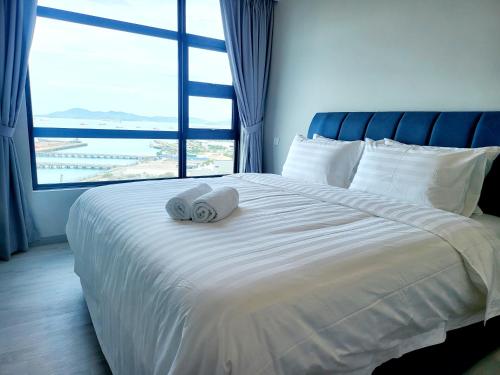 a bed with two towels on it with a large window at Kota Kinabalu Jesselton Quay Seaview with washing machine in Kota Kinabalu