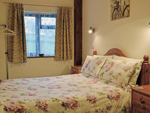 1 Schlafzimmer mit einem Bett mit Blumenbettdecke und einem Fenster in der Unterkunft Oakwood Venbridge Farm in Cheriton Bishop