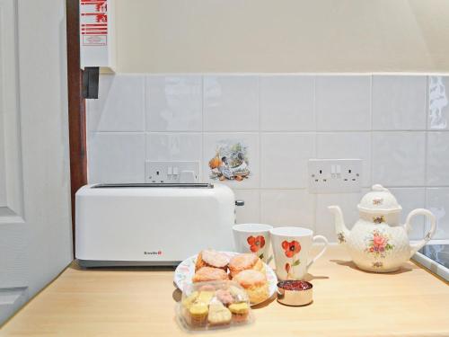 a kitchen with a counter with pastries and tea cups at Oakwood Venbridge Farm in Cheriton Bishop