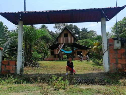 een jongen die onder een paviljoen voor een huis zit bij FINCA AGROTURISTICA VILLA MANE in San José del Guaviare