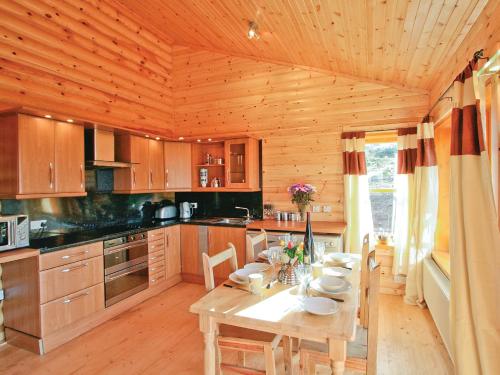 uma cozinha em madeira com uma mesa num camarote em Bracken Log Cabin - S4468 em Glenfarg