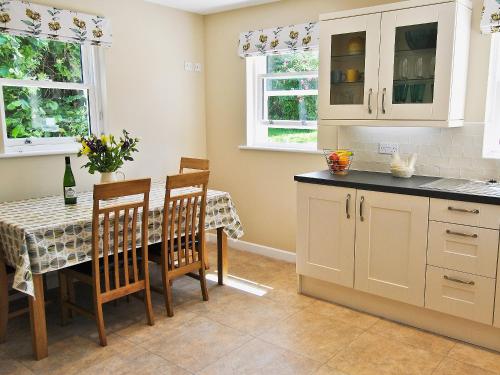 a kitchen with a table and some chairs and a table and cabinets at Bramble Cottage in Wimborne Minster