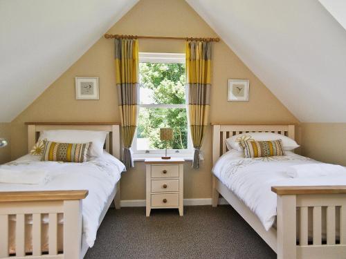 two beds in a attic bedroom with a window at Bramble Cottage in Wimborne Minster
