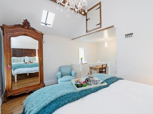 a bedroom with a bed with a blue blanket and a mirror at The Wee House On The Hill in Wirksworth