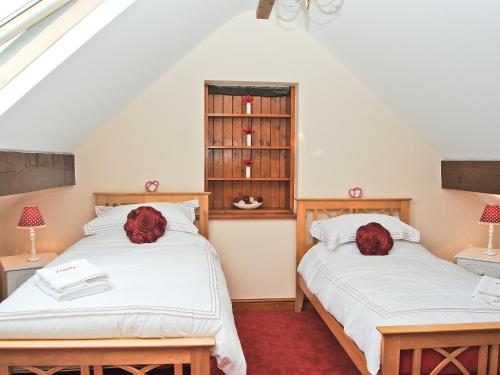 two beds in a attic room with red roses on them at Ysgubor in Harlech