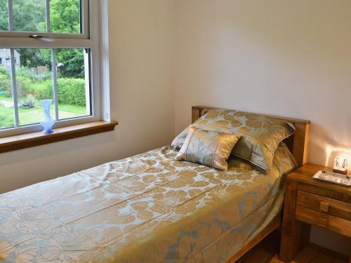 a bedroom with a bed with a pillow and a window at Ivy Cottage in Kielder