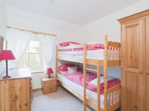 Holly Cottage في Bellerby: غرفة نوم مع سريرين بطابقين مع ملاءات وردية