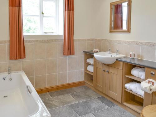 a bathroom with a tub and a sink at Bank Top Cottage in Cropton