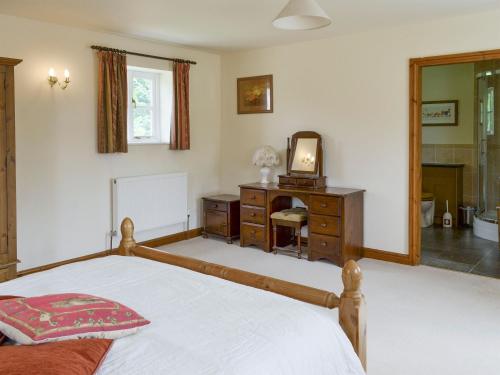 a bedroom with a bed and a dresser and a mirror at Bank Top Cottage in Cropton