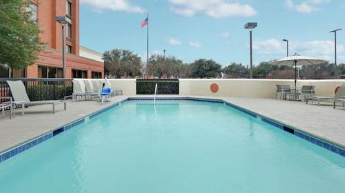 a large swimming pool with chairs and an umbrella at Comfort Inn Plano-Dallas in Plano