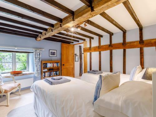 two beds in a room with wooden beams at Mill Cottage in Bampton