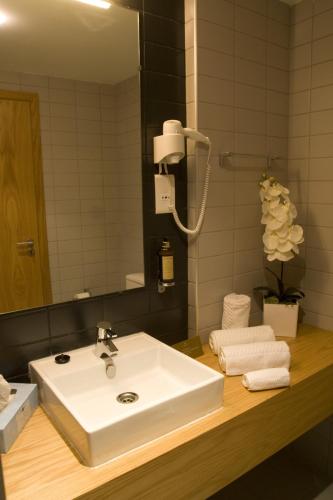 a bathroom with a white sink and a mirror at Paredes Hotel Apartamento in Paredes