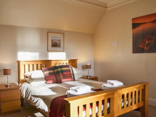 a bedroom with a wooden bed with two pillows at Treetops in Newtonmore