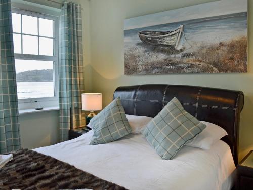 a bedroom with a bed with a window and a painting at Seaview in Garlieston