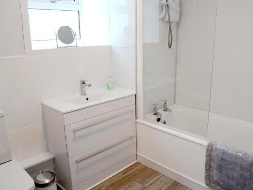 a white bathroom with a sink and a shower at Bydand Cottage in Melness