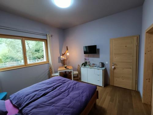 Gantrisch Lodge في Rüschegg: غرفة نوم بسرير ارجواني ونافذة