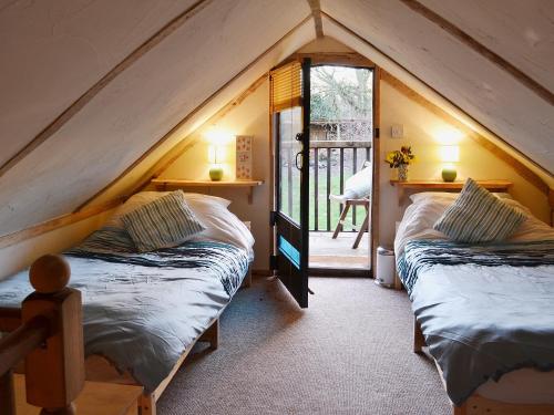 2 Betten in einem Dachzimmer mit Fenster in der Unterkunft Robins Nest - 29409 in Elmsted