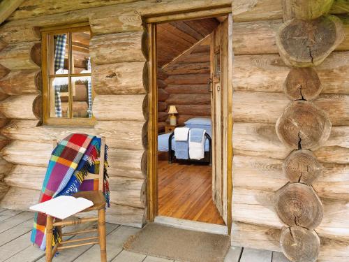 a door to a log cabin with a chair and a bed at The Shooting Lodge in Acton Scott