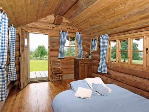 1 dormitorio con 1 cama en una cabaña de madera en The Shooting Lodge, en Acton Scott