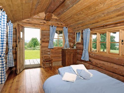 una camera con un letto in una baita di tronchi di The Shooting Lodge ad Acton Scott