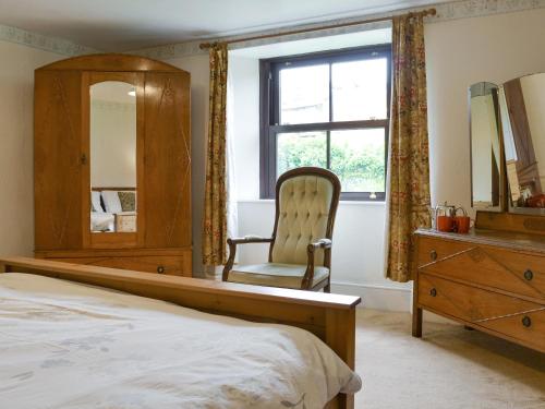 a bedroom with a bed and a chair and a mirror at Tutchenor Farmhouse in Beaworthy