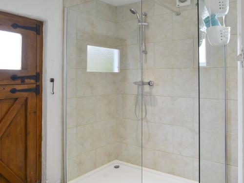 a bathroom with a shower with a glass door at Tutchenor Farmhouse in Beaworthy