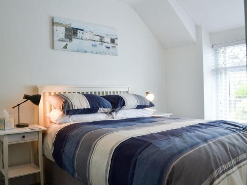 a bedroom with a bed with blue and white sheets at Wendon in Criccieth