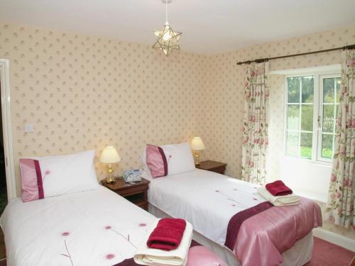 2 Betten in einem Zimmer mit rosa und weiß in der Unterkunft Bickley School House in Broxa