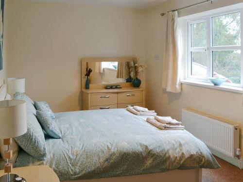 a bedroom with a bed with a dresser and a mirror at Ryandale in Longhirst