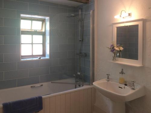 een badkamer met een bad, een wastafel en een bad bij Oaktree Cottage in Appledore