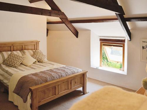 a bedroom with a wooden bed and a window at Dover Row Cottage in Zelah