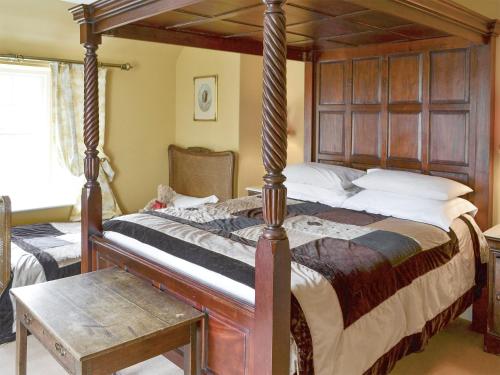 a bedroom with a four poster bed with a wooden headboard at Lochside Garden House - S4484 in Town Yetholm