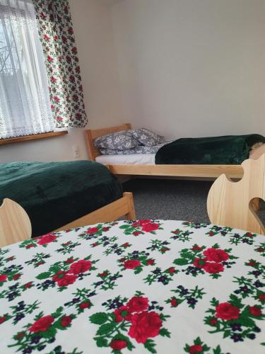 a room with two beds and a blanket with red flowers at Przy Tartaku in Jurgów