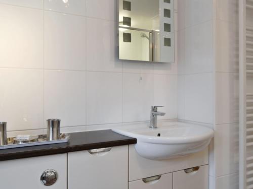 La salle de bains blanche est pourvue d'un lavabo et d'un miroir. dans l'établissement High Rigg, à Keswick