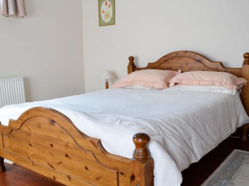 Schlafzimmer mit einem Holzbett mit weißer Bettwäsche und rosa Kissen in der Unterkunft Daisy Cottage in Chipping Sodbury