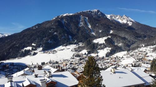 a town in the snow with a mountain in the background at Ciasa Alpina Relax Hotel in Moena