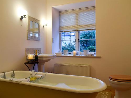 a bathroom with a tub and a sink and a window at Apple Cottage in Forgandenny